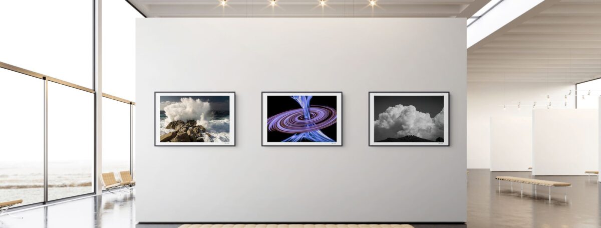 stan weyler art gallery presentation of artistic fine art prints on display. there are three artwork samples on the gallery wall. first to the left is the Dramatic Corsica Seascape Print, Golden Hour Crashing Wave Wall Art from the liquid serenity collection. in the middle is the Flux Malva Cosmic Energy Jet Print, Abstract Astrophotography, Sci-Fi Space Art (Archival Giclée) from the cosmic visions collection. to the right ist the Dramatic Storm Clouds Corsica Landscape Photography – Minimalist Nature Wall Art Print from the corsica discovery collection.